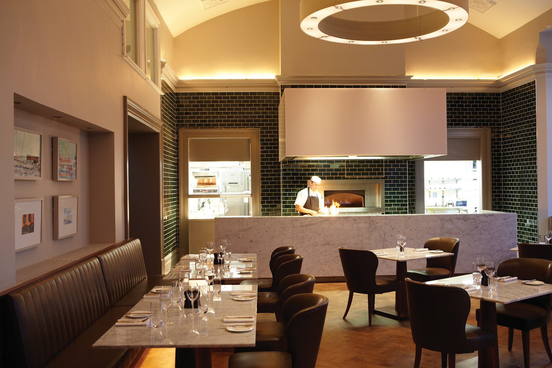A restaurant with tables, chairs, and a chef in the background.