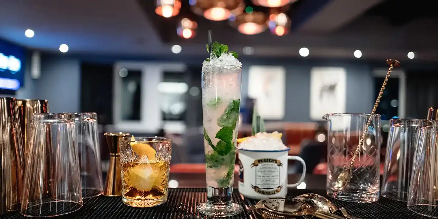 A table with a tall glass and a smaller glass containing cocktail beverages.
