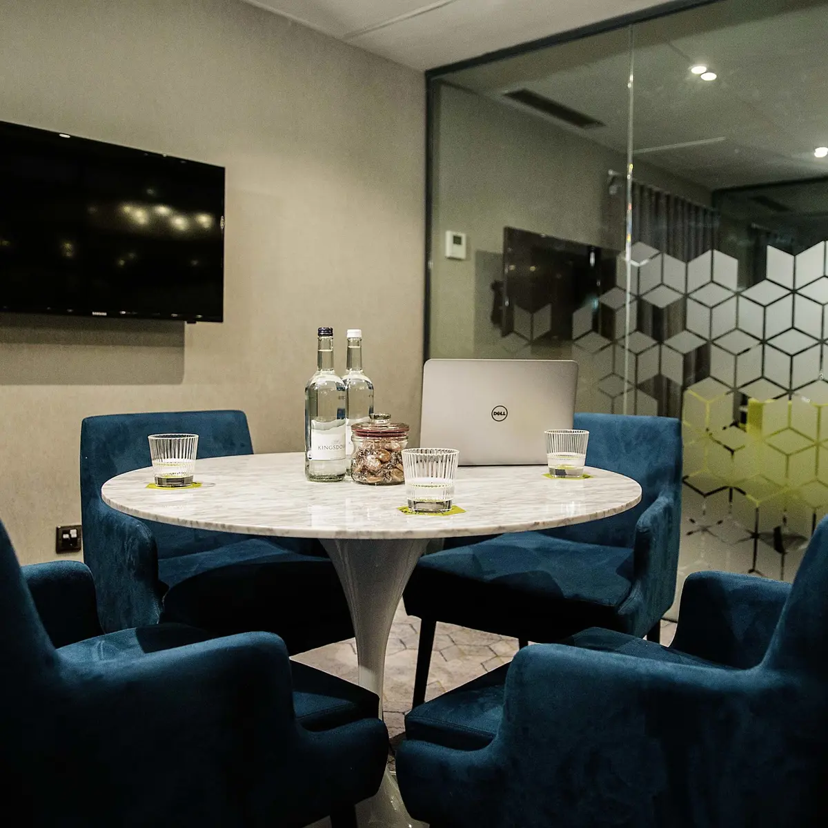 A well-furnished meeting room featuring a table, chairs, and a television.