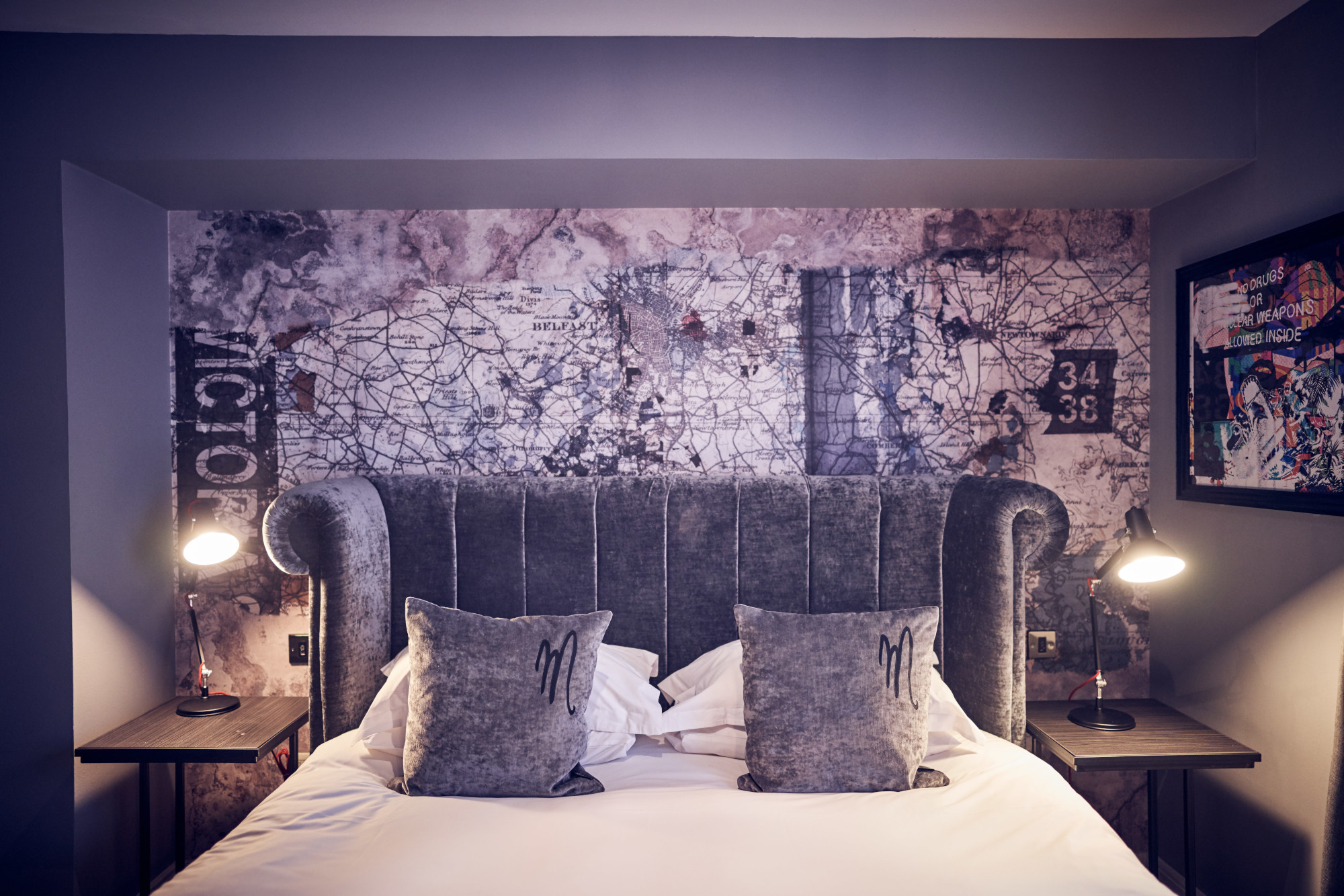 A bed featuring a grey velvet headboard adorned with plush pillows.
