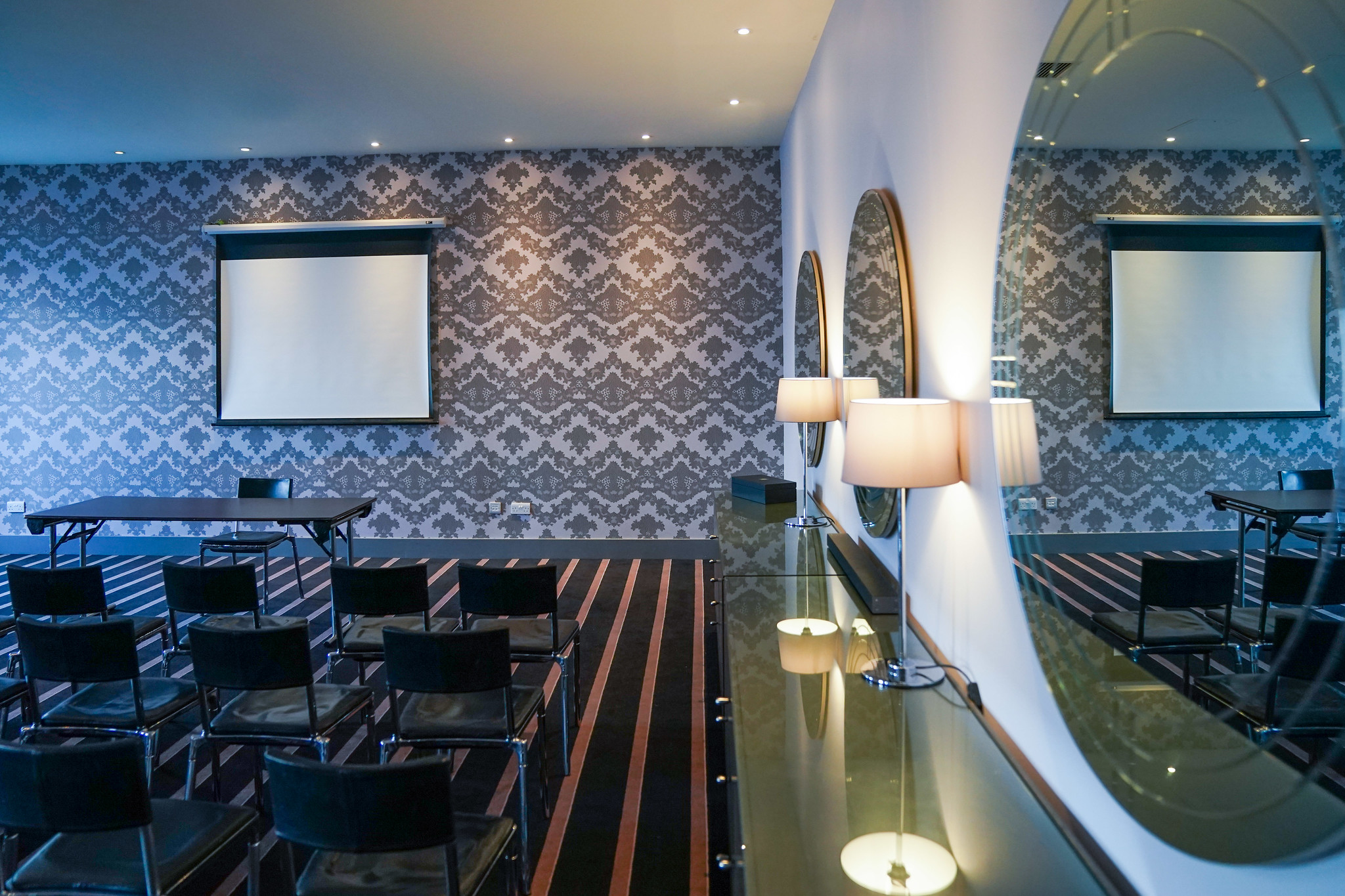 A room furnished with a mirror, chairs, and a table.