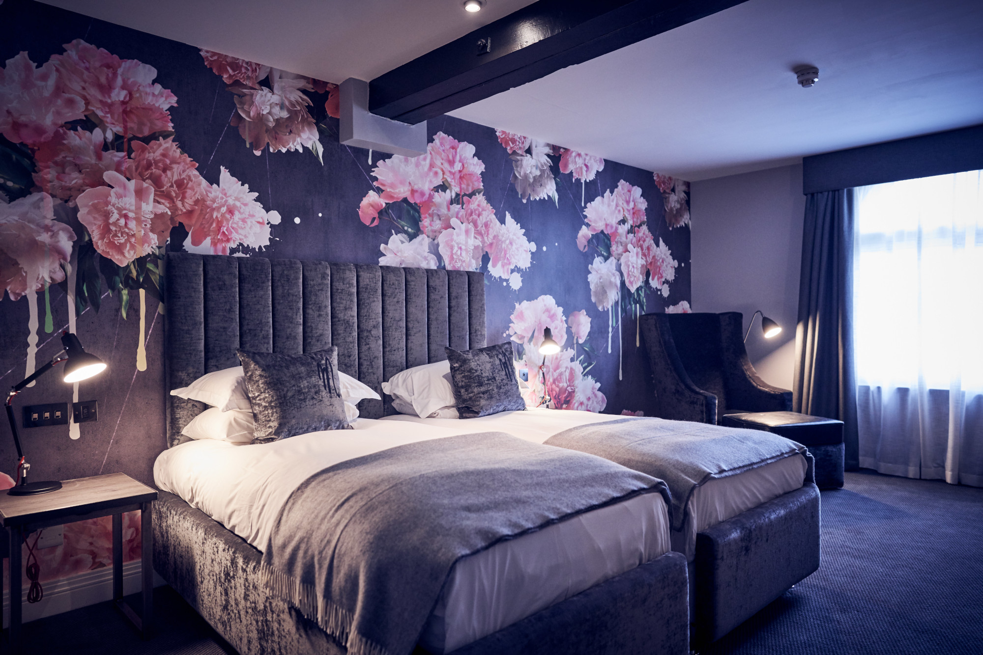 Two beds and a chair in a bedroom.