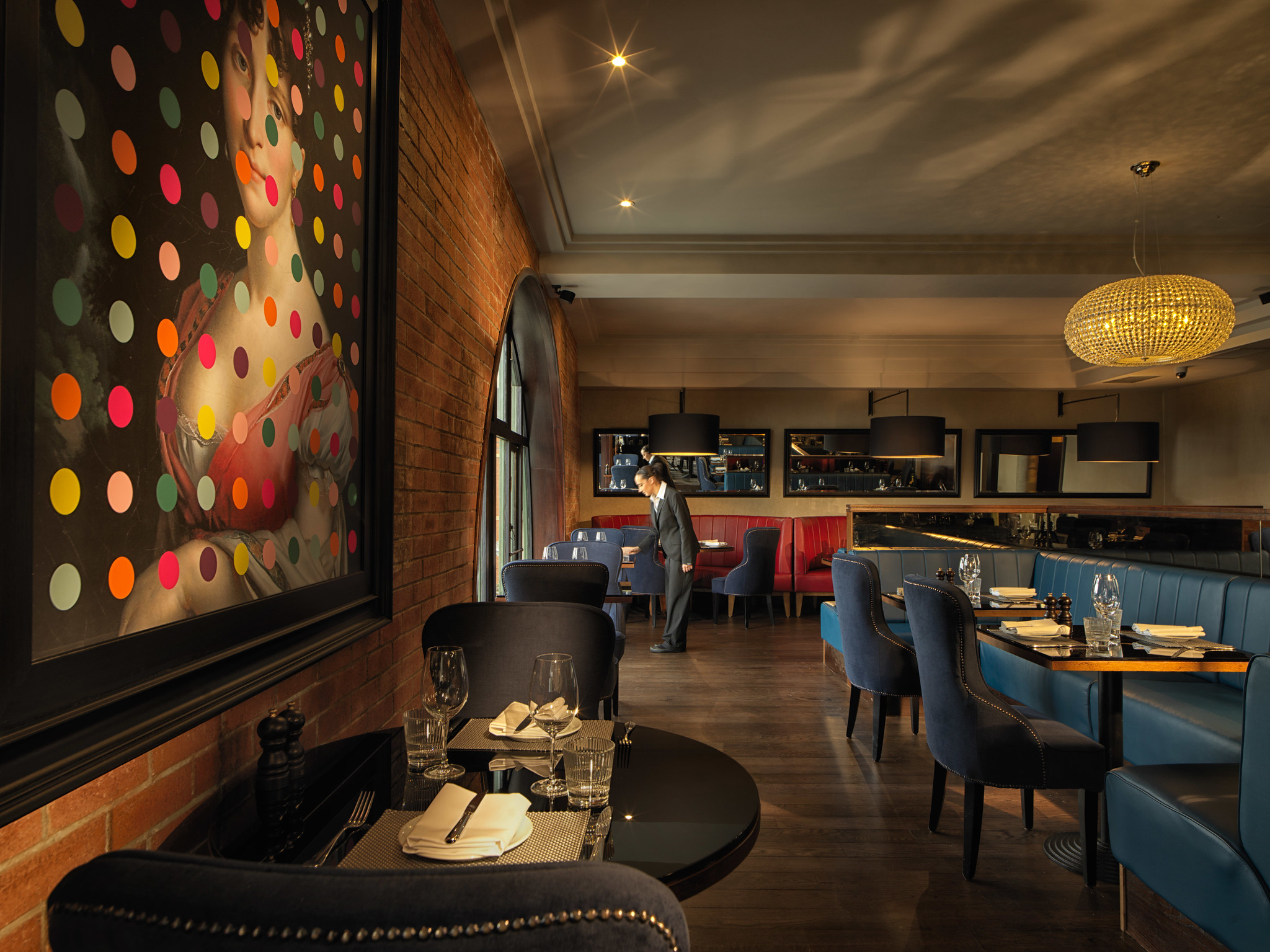 A restaurant featuring tables, chairs, and a wall adorned with a painting.